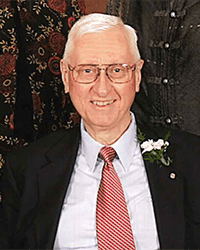 Headshot of J. William Click in a suit and tie wearing a white carnation on his lapel