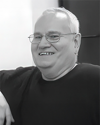 Greyscale headshot of c Marshall Matlock, laughing