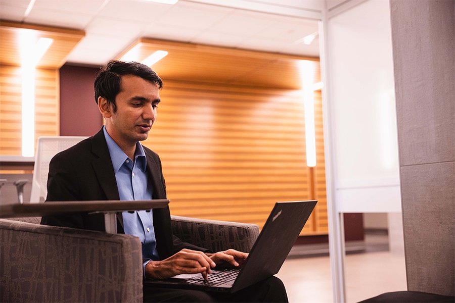 Man sitting in chair using a laptop in a lounge
