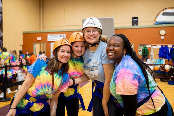 A group of students inside Adventure Seminars wearing climbing helmets and standing together.