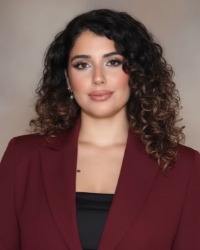 2026-04-10-Nisreen-Allen-01-200x250 Headshot of Nisreen Allen wearing a maroon blazer against a grey background.