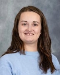 2026-04-10-Reanna-Averill-01-200x250 Headshot of Reanna Averill wearing a blue sweater against a grey background.