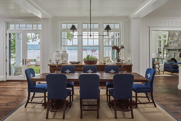 a dining room with windows that overlook a lake with a 8 person table and chairs
