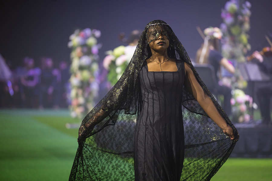 a woman modeling a black dress with a long, lace, black veil