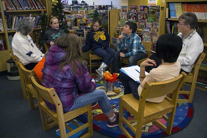 group of adults and kids talking in a library setting