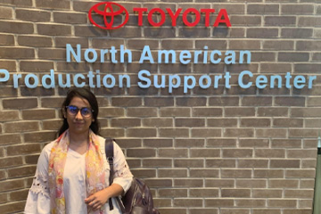 A Master of Science in Administration student standing in front of Toyota office building.