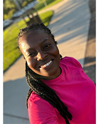 Christine- MSA Peer Mentor, standing outside wearing a pink shirt while smiling for a photo.