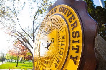 The CMU Seal outside during the day.