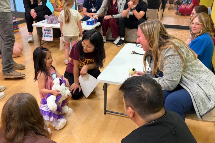 2026-06-17-Teddy-Bear-Clinic-02-720x480 A group of PA students sitting around a table talking to a child holding a stuffed animal.