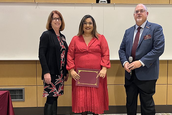 Alumni award recipient Isabel Montemayor holds a certificate and stands between Associate Dean Marcy Taylor and Dean Richard Rothaus.