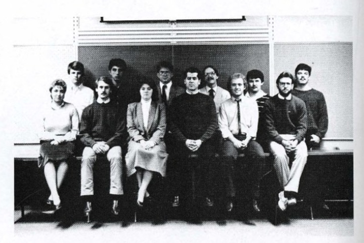 Black and white image from 1985 showing Model UN Club students seated and standing in two rows in front of a classroom chalk board.