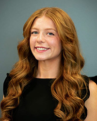 20250904_TeagenSchultz_200x250 A woman with long wavy red hair smiling.