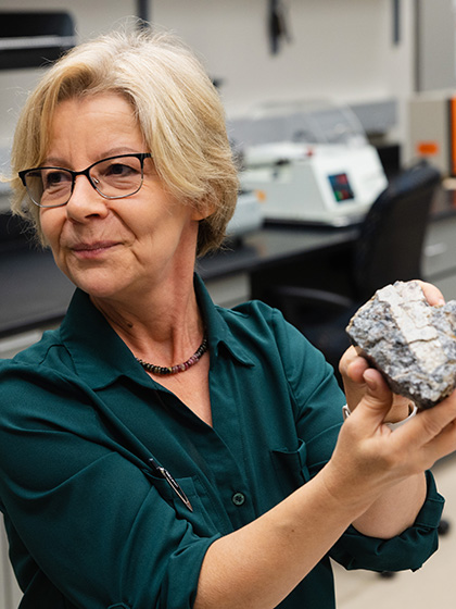 A faculty member in a blue shirt holding a rock sample