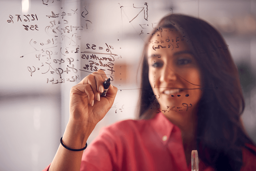A woman in a pink blouse solves a math equation.