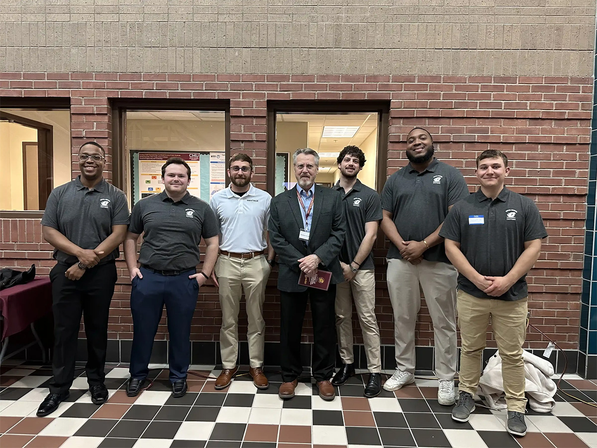 A group of men standing in front of a brick wall
