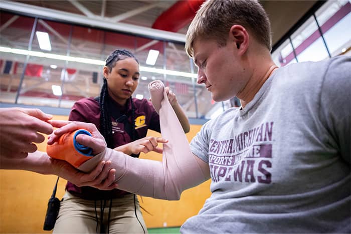 An athletic training student splints an individual's arm.