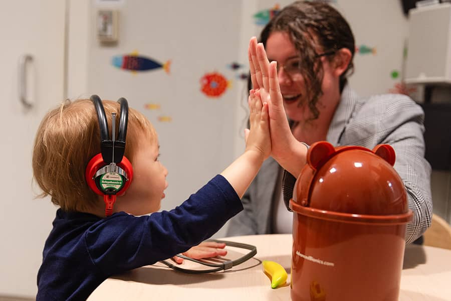 Speech Language Pathology student and toddler giving each other a high five.