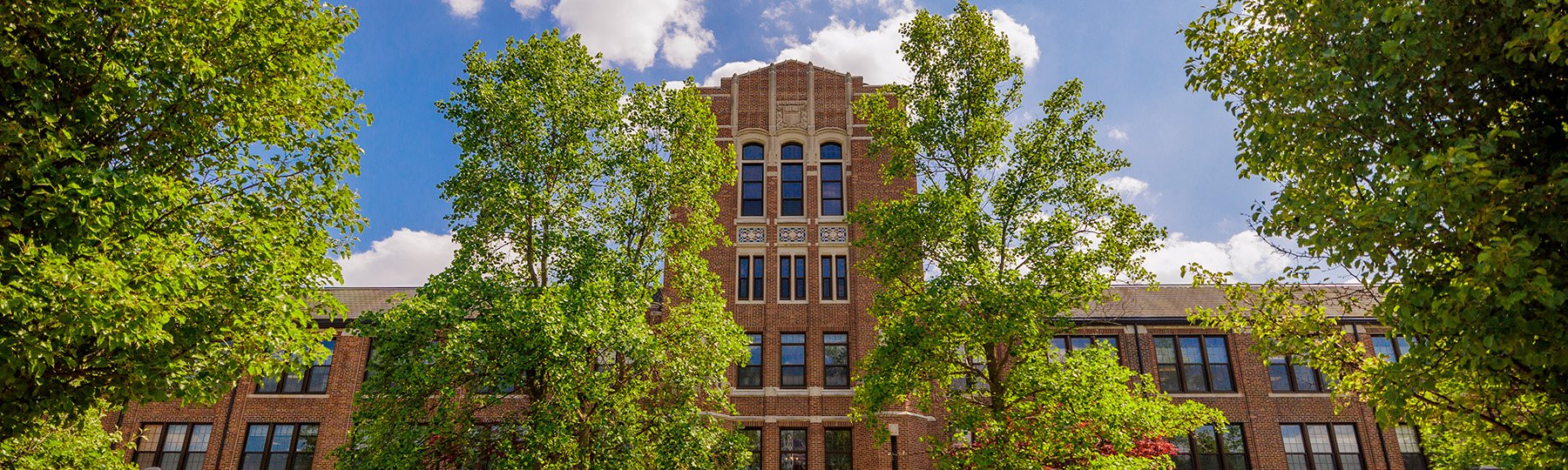 2023-269-0014-Warriner-Payroll-1800x540 Straight-on view of Warriner Hall on a bright summer day.
