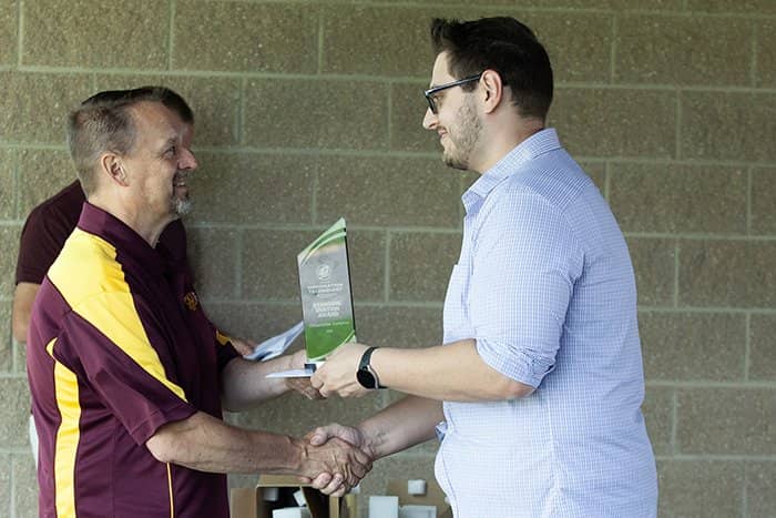 The CIO of OIT at CMU hands a glass award to a staff member.