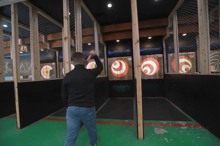 A person throws an axe at a target.
