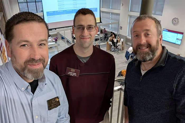 Three smiling OIT team members pause to take a selfie while overlooking the Grawn Hall atrium during the annual Business Professionals of America day.