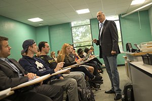 A College of Business Administration professor talks with his students in a business classroom.