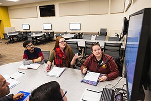A group of five diverse math students sits around a table in college classroom.