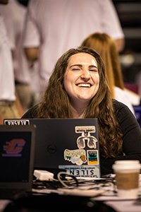 A woman smiling at a laptop.