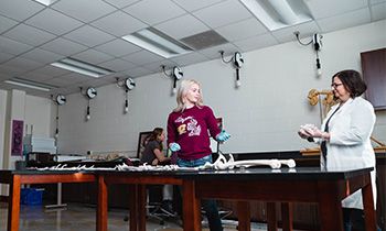 A student and faculty member examine a 3D-printed skeleton.