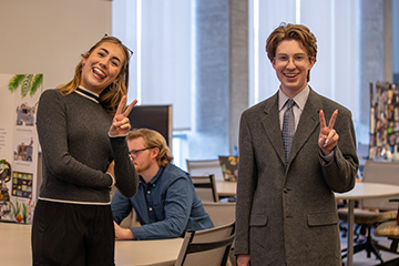 A man and woman smiling and giving peace signs.