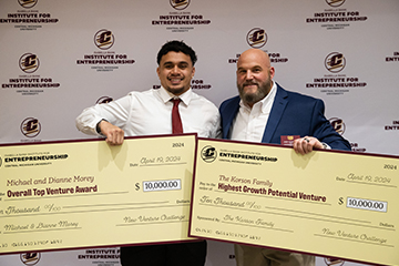 Two men holding up two large checks.