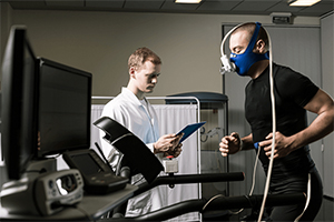 A man runs on a treadmill with a breathing mask