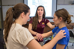 a group of women in a classroom studying each others arms and hands to learn the different anatomy