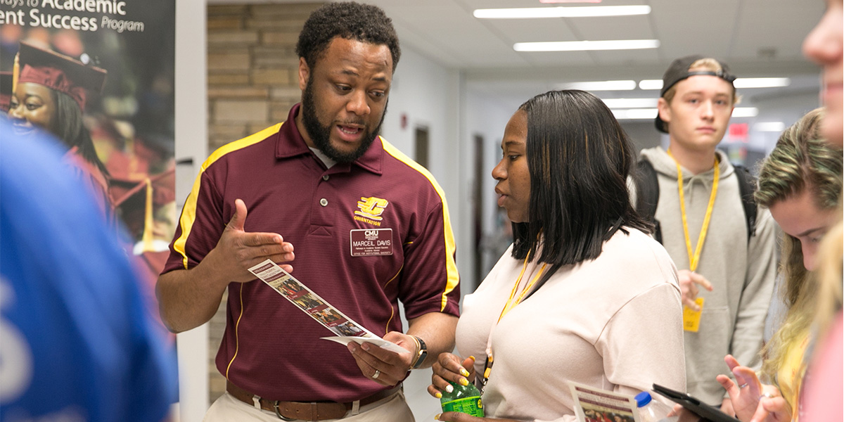 A CMU staff member talks to a supporter gesturing to a pamphlet