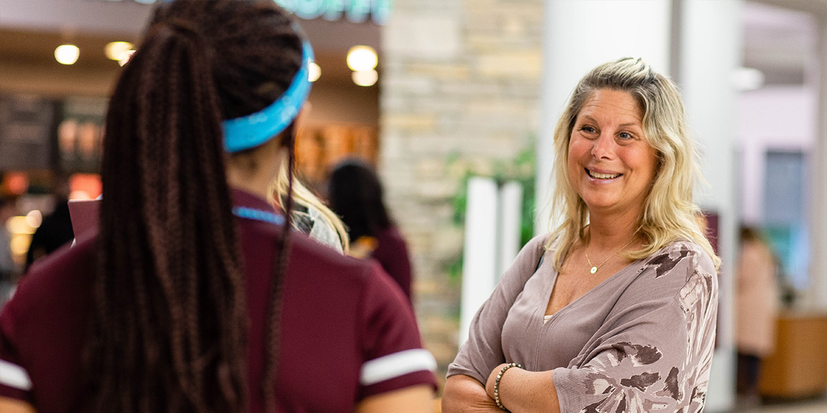 A women smiles at an orientation leader with her arms crossed