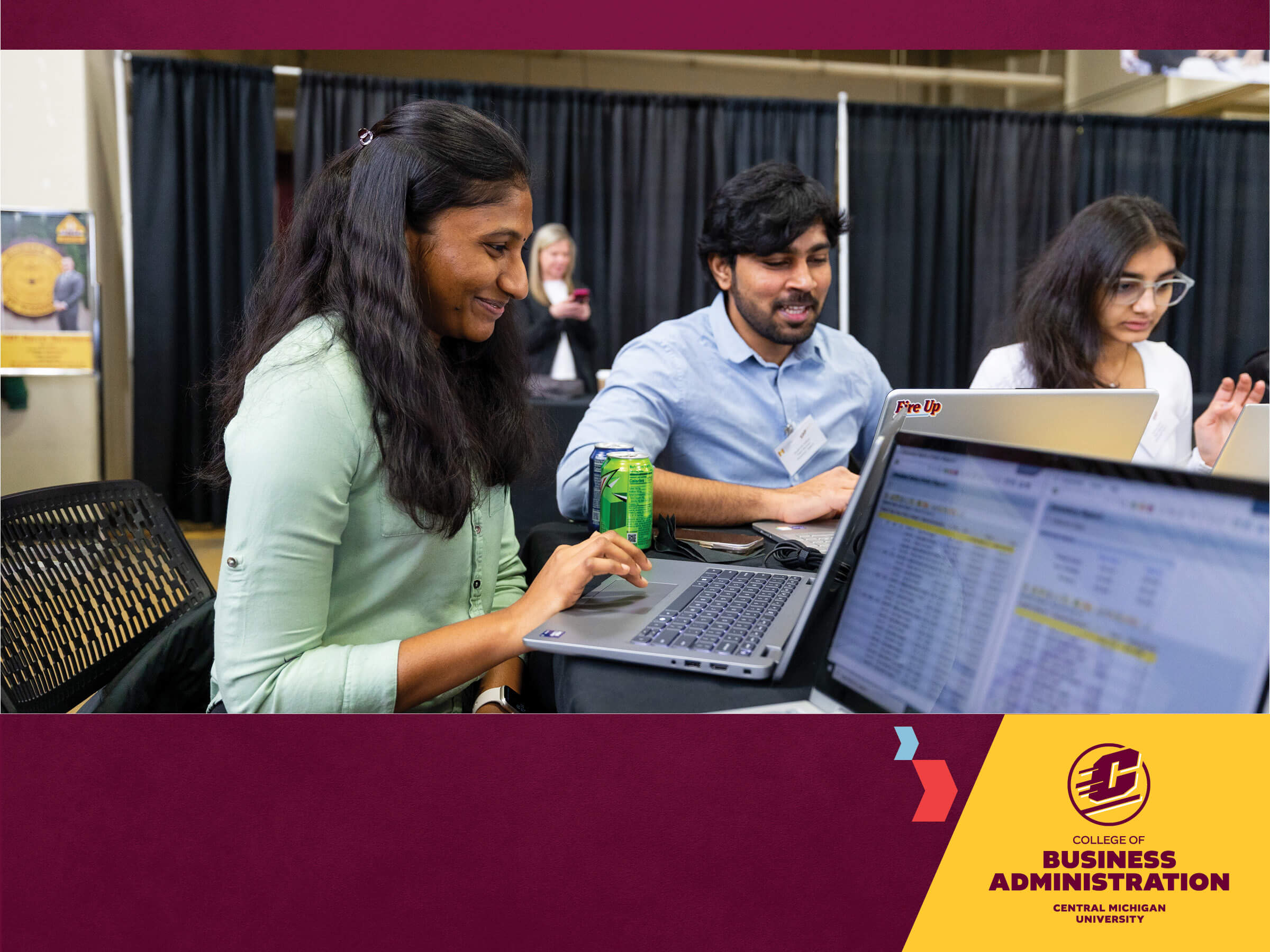 a group of students sitting at a table looking at a laptop