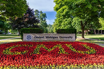 A flower bed planted with yellow flowers spelling CMU on a background of red flowers.