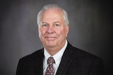 A man with white hair in a suit and tie.