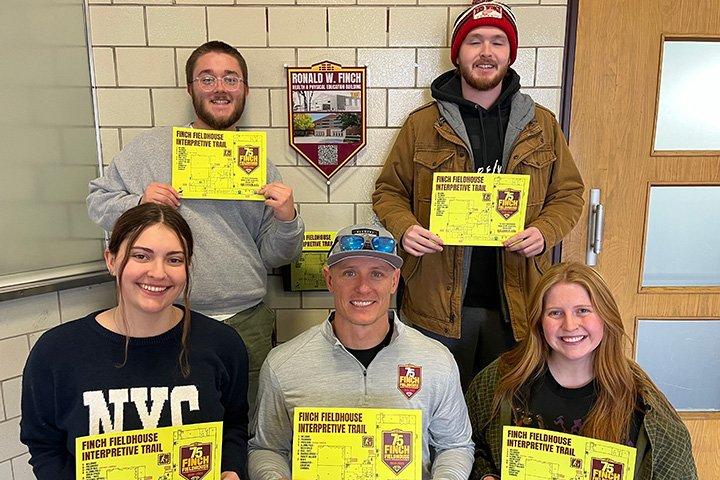 Five people arrayed in two rows, all are holding yellow signs.