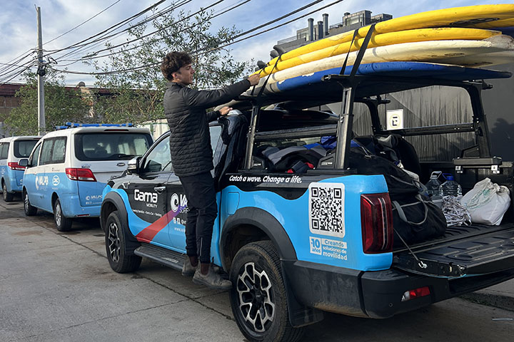 A young man straps surf boards down to the top of a jeep.