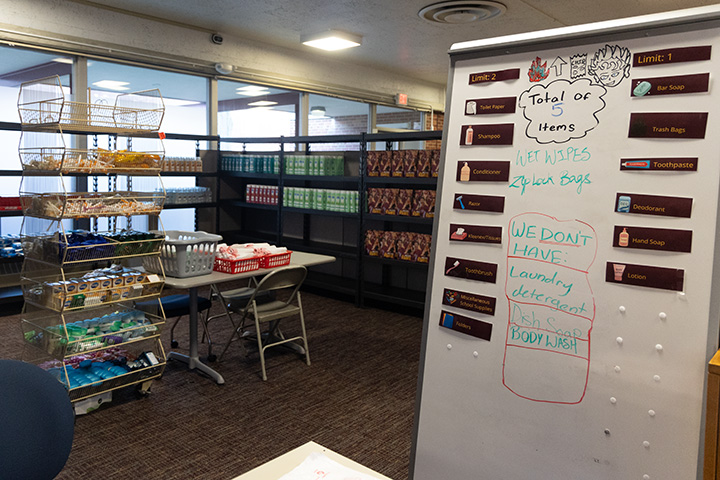 A white eraser board with a list of care items in stock and a list of care items not in stock sits in front of full shelves on storage racks.