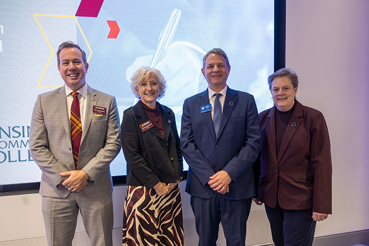 Four people, including CMU's president and provost, stand in front of a projector screen