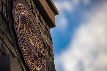 A maroon and gold sign on a brick wall.
