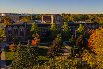 A view from above of a large brick building surrounded by colorful trees.