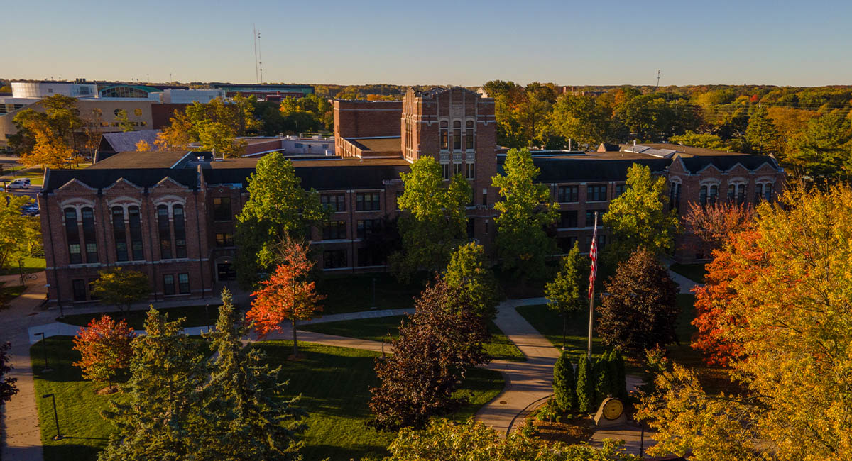A view from above of a large brick building surrounded by colorful trees.
