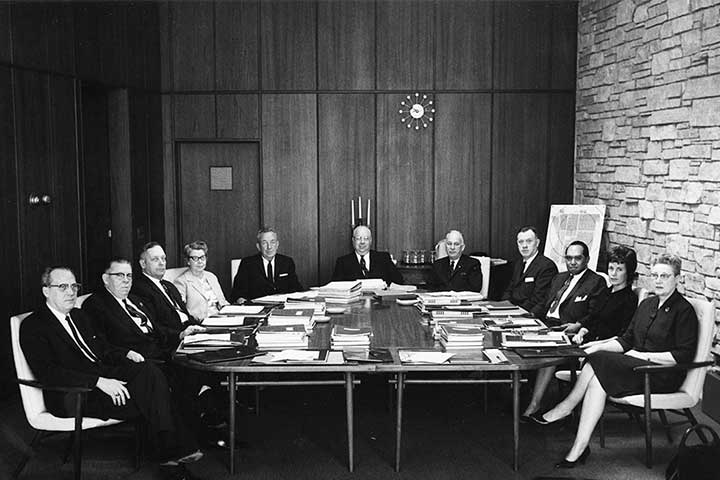A black and white photo of a 1964 meeting of the CMU Board of Trustees, with 11 people seated around a large table