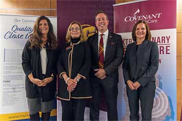 A group of 4 people stand in front of banners at an announcement ceremony