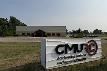 A closeup view of the CMURC sign with the CMURC building in the background.