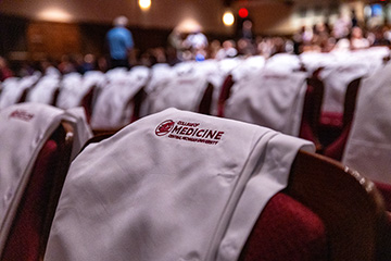 A group of chairs with white shirts with the words CMU College of Medicine on them