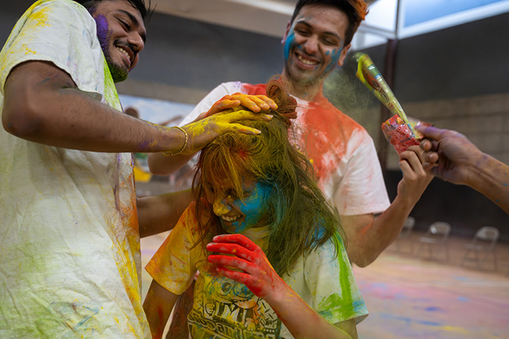 Three students covered in colored powder celebrate Holi, the Hindu festival of colors.